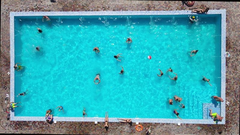 Raw pool camera feed showing overhead view of busy swimming pool